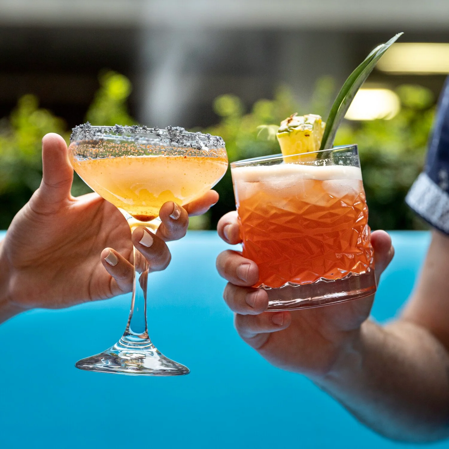Two guests raising cocktails beside a Cabo pool